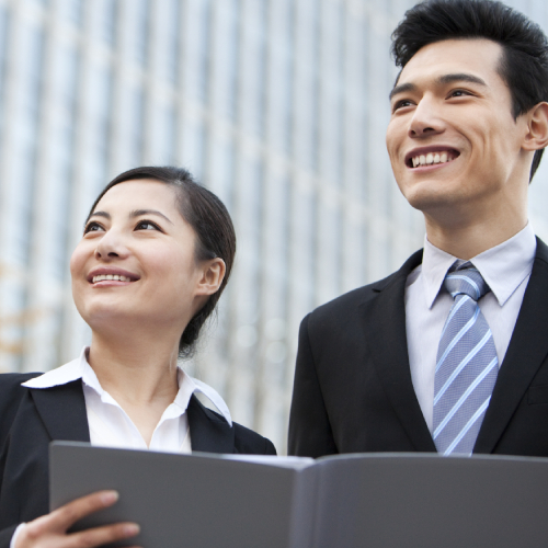 A businessman and businesswoman outside office buildings with a document