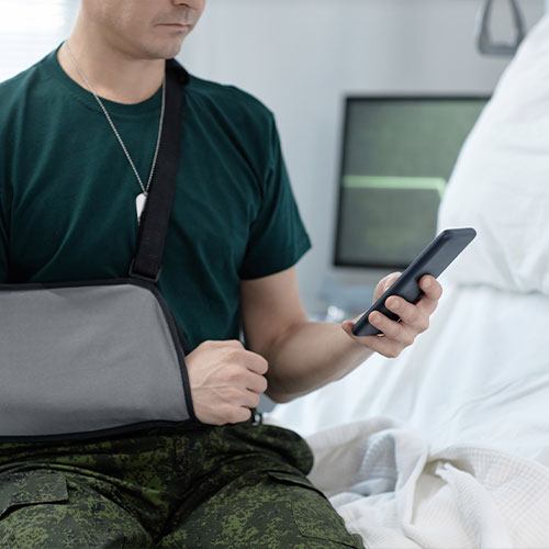 Soldier reading message on mobile phone in hospital
