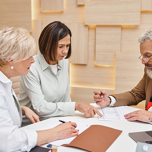 realtor showing blueprint of apartment to middle aged interracial lgbt couple in real estate office