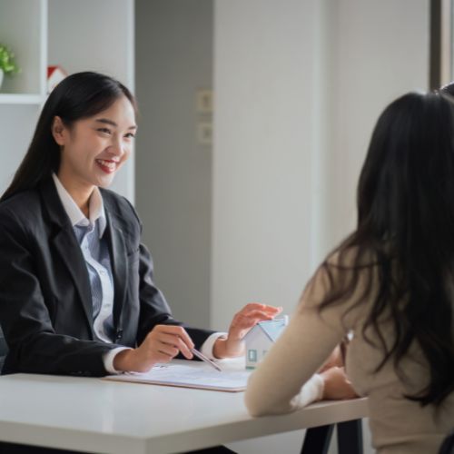 Young Asian couple making contract with house sale agency. man and his wife sitting signing the