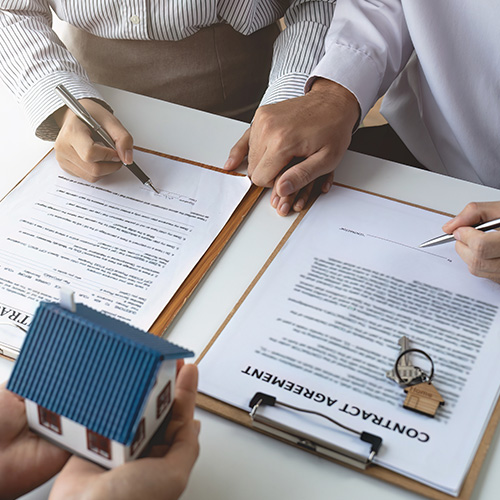 Real estate agent with couple closing a deal and signing a contract.