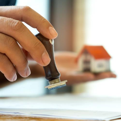 Hand stamping paper with model house in background